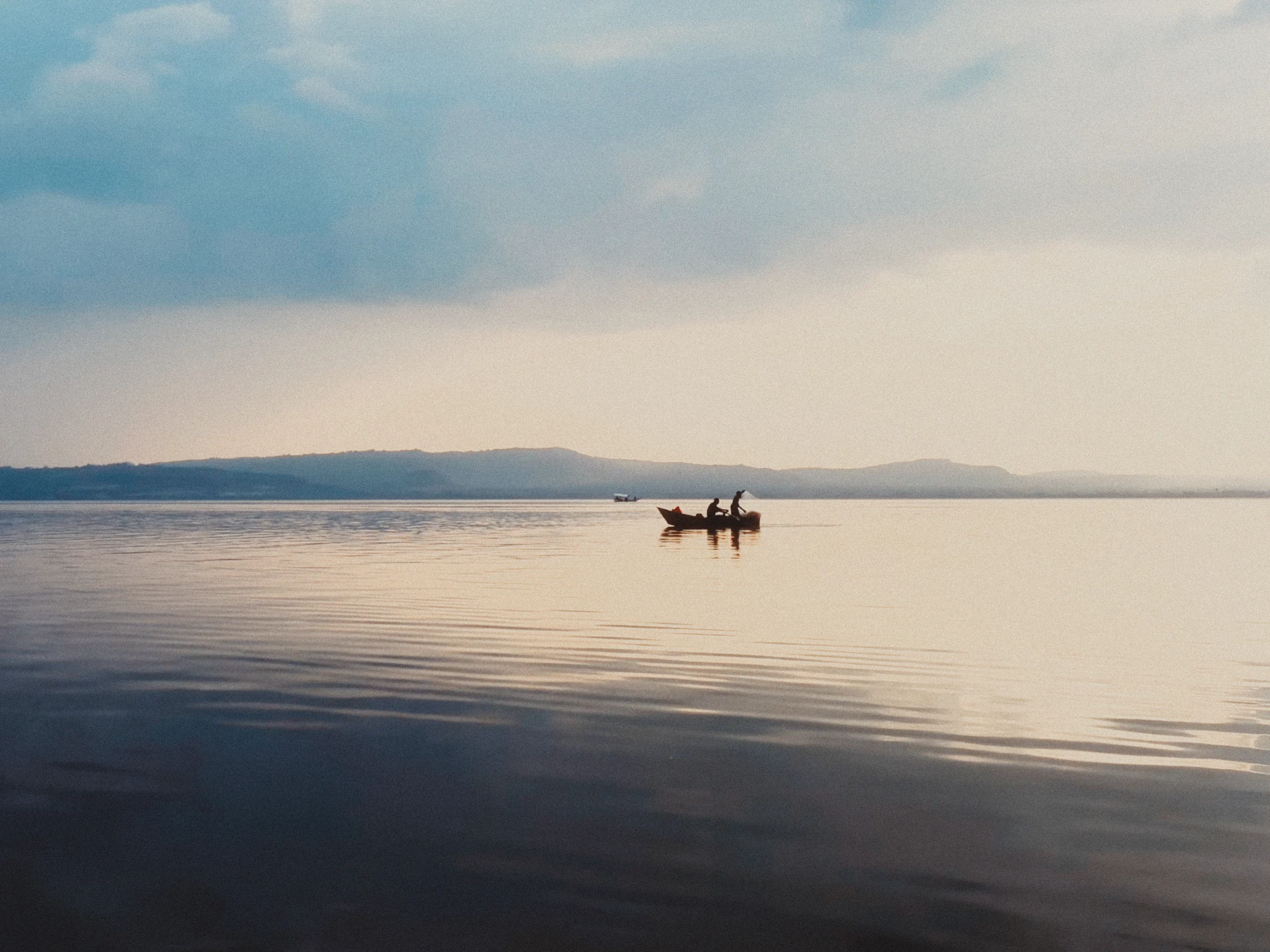 A small boat framed against a quiet lake and distant mountains