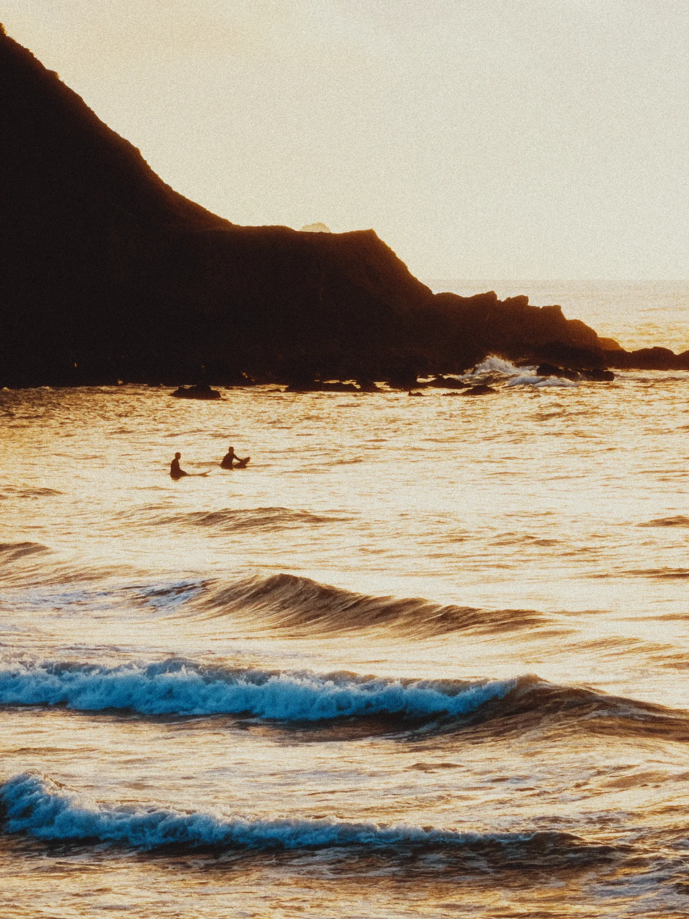 Surfers in warm evening light with blue waves, developed with KG 200
